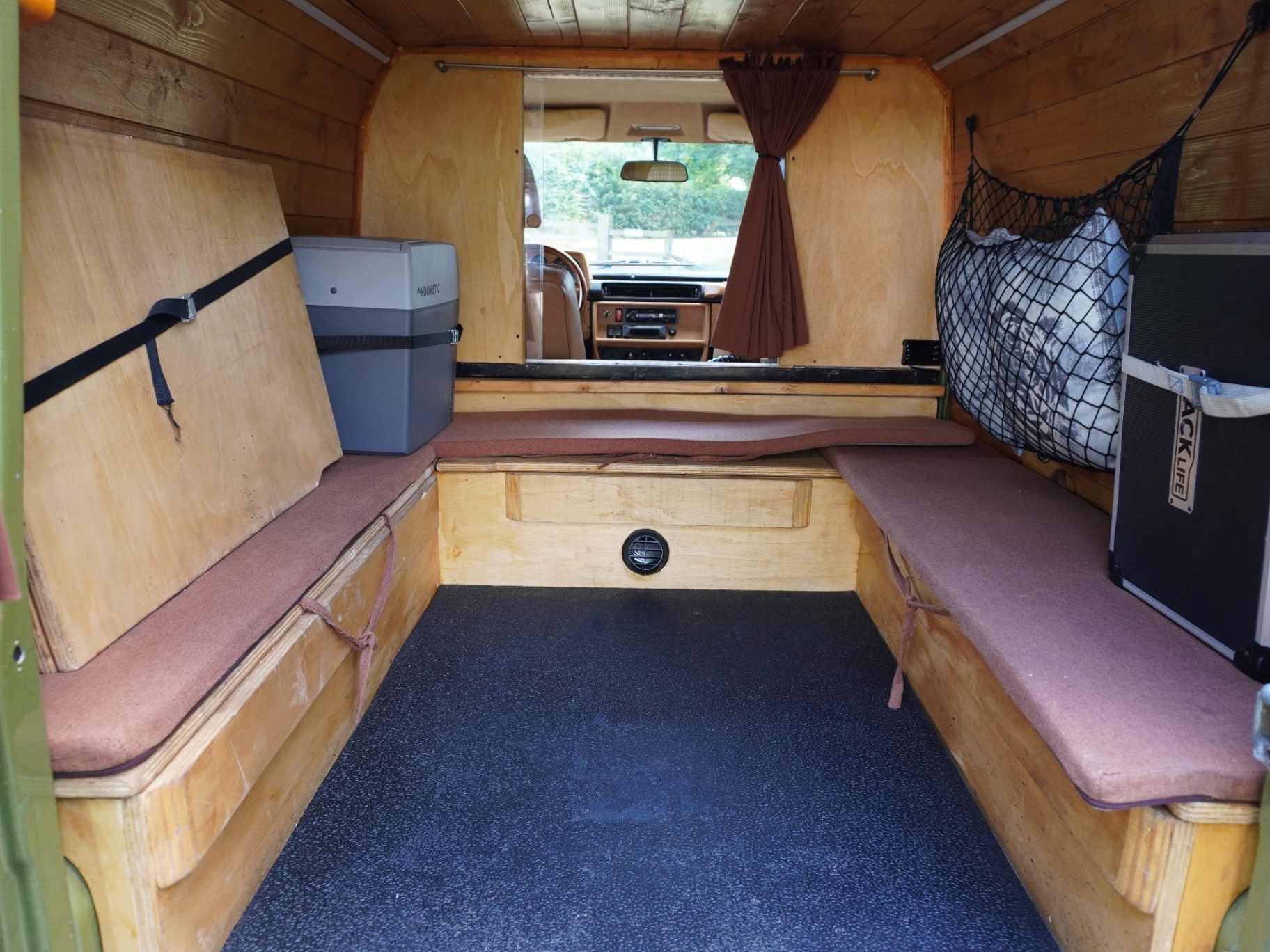 Wood-lined rear camper conversion with benches and storage